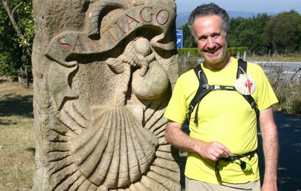 A hiker on the Camino de Santiago. The stone marker features the scallop shell - the iconic symbol of this famous pilgrimage walk.