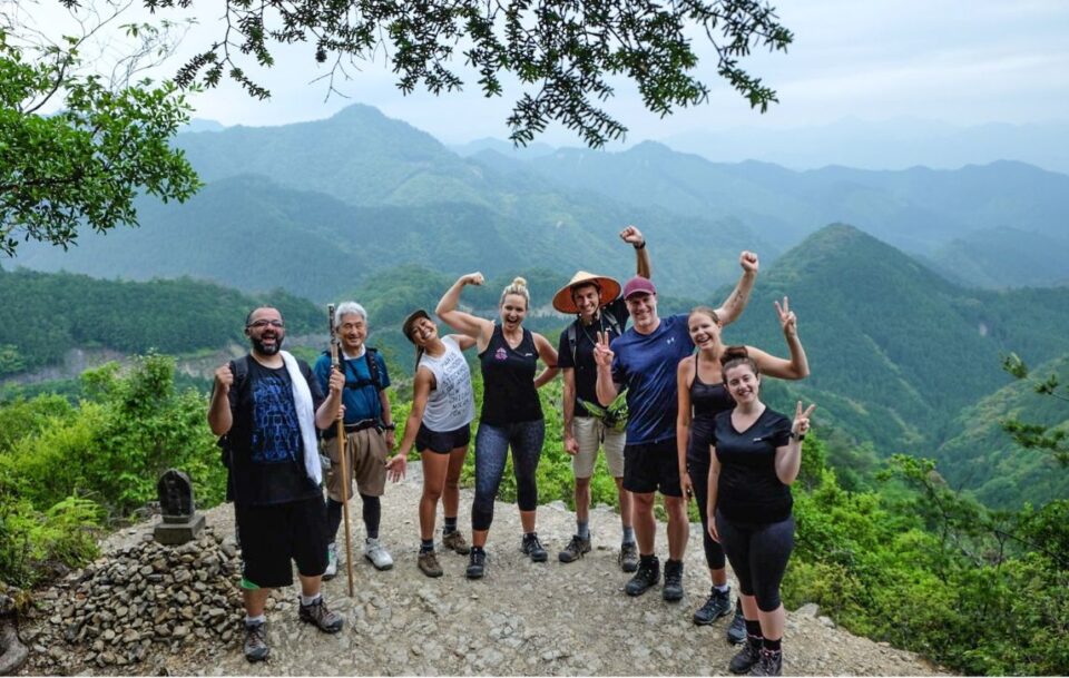 Group of hikers at the top of a hill with mountains in the background.