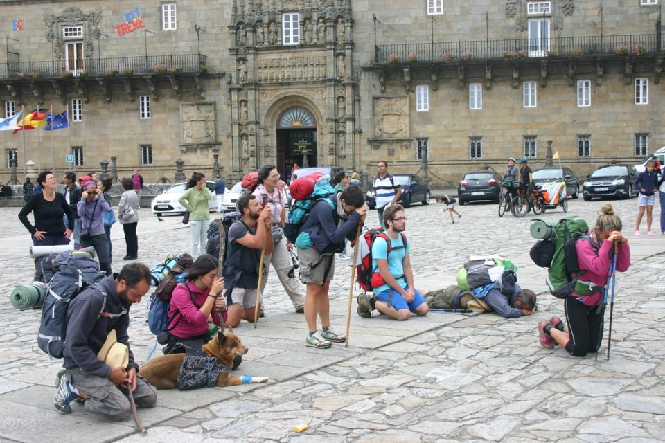 A large group of Camino pilgrims in the main square of the Santiago Cathedral, reflecting on their pilgrimage