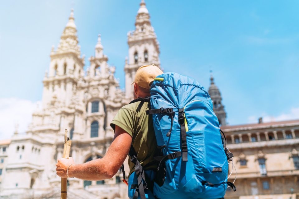Rear view of a male pilgrim in he main square of Santiago de Compostela looking up at the famous Cathedral.