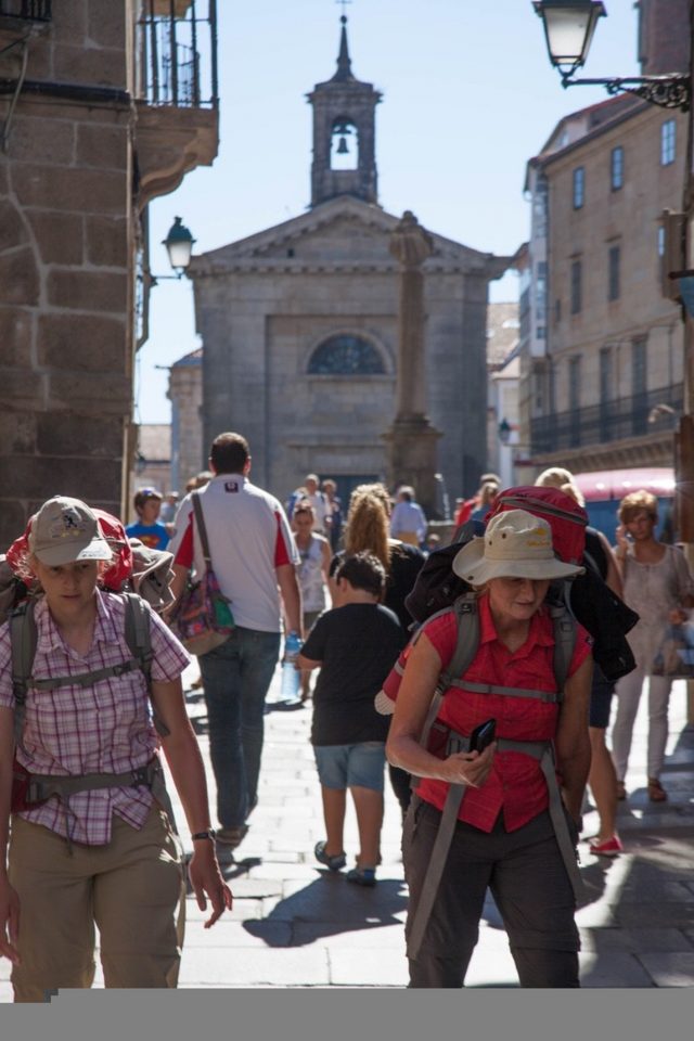Female pilgrims and tourists in a crowded street in Santiago de Compostela during a Holy Year.