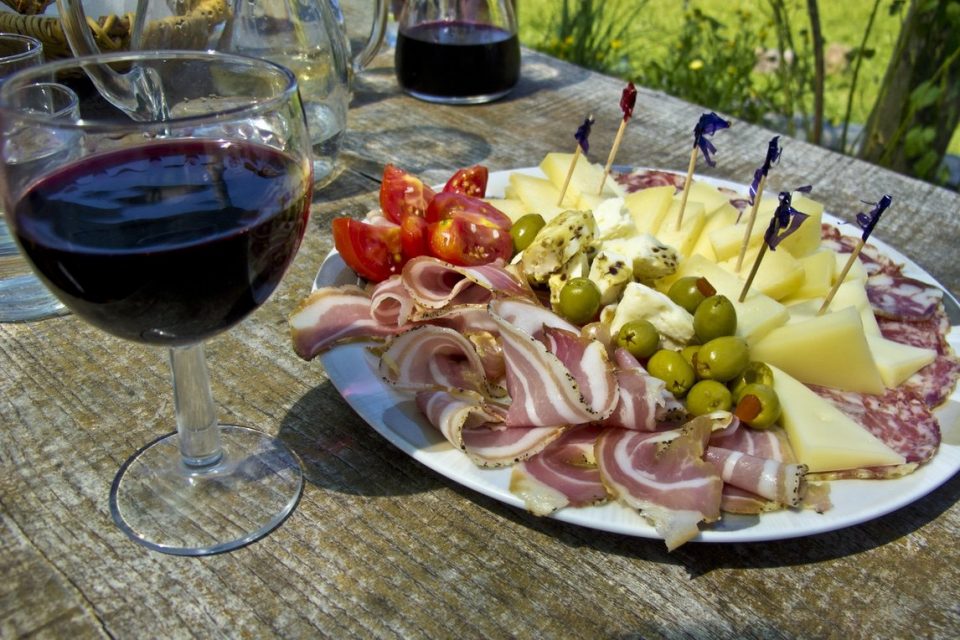 Food in Spain often involves various Spanish cheeses and meats on a platter, with a glass of red wine