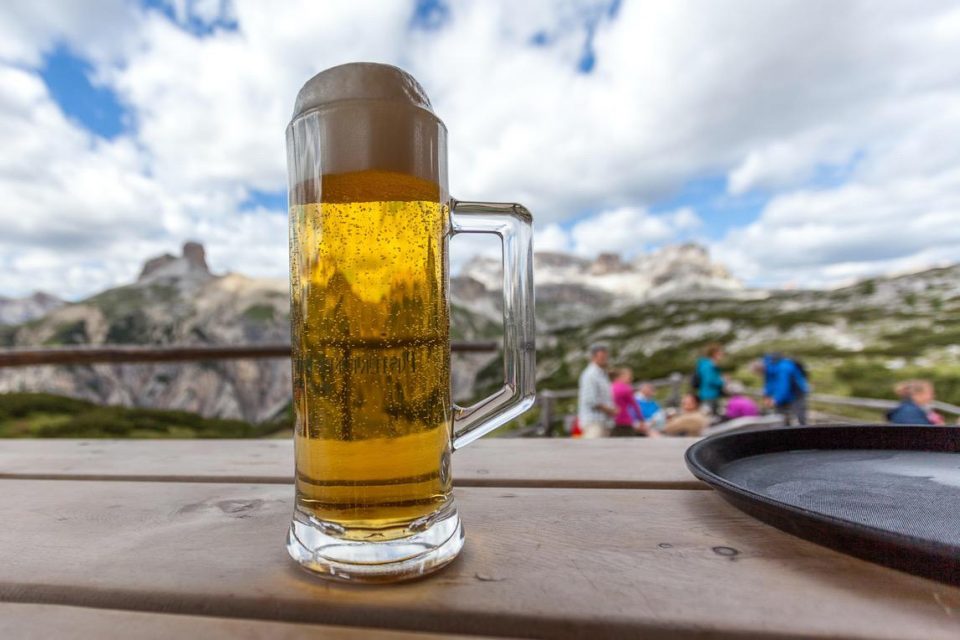 Mug of beer in a dolomite refuge with mountain background, South Tyrol, Dolomites, Italy