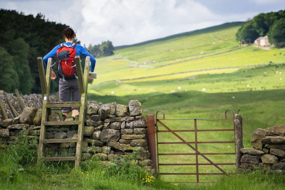 Hiker climbing over stile