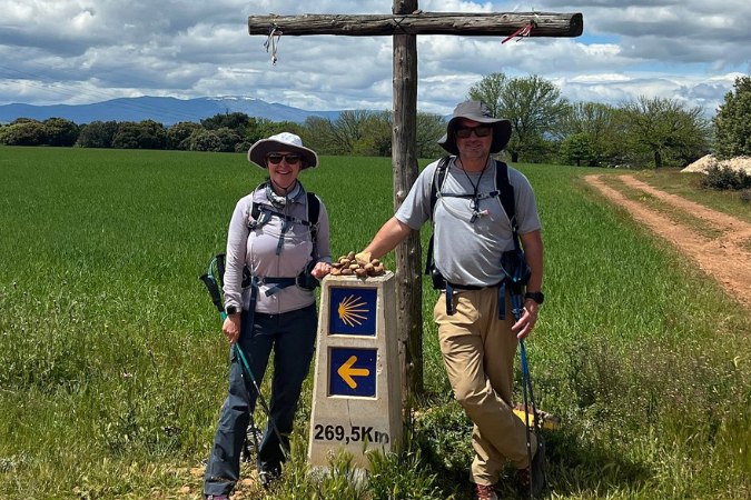 Two hikers next to a Camino stone marker smiling at the camera