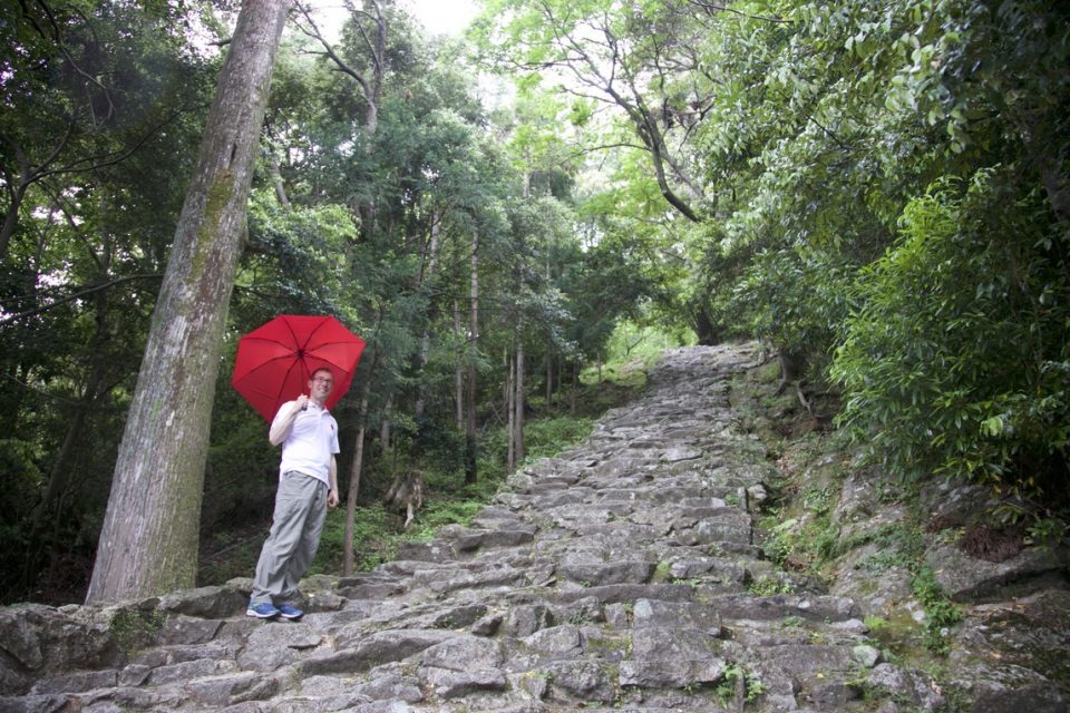 Walker holding umbrella along Kumano Kodo trail.