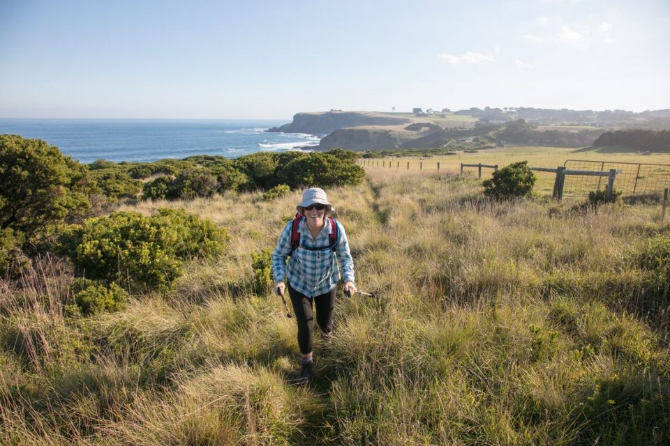 Female hiker walking through coastal grassland near the coast on the Mornington Peninsula