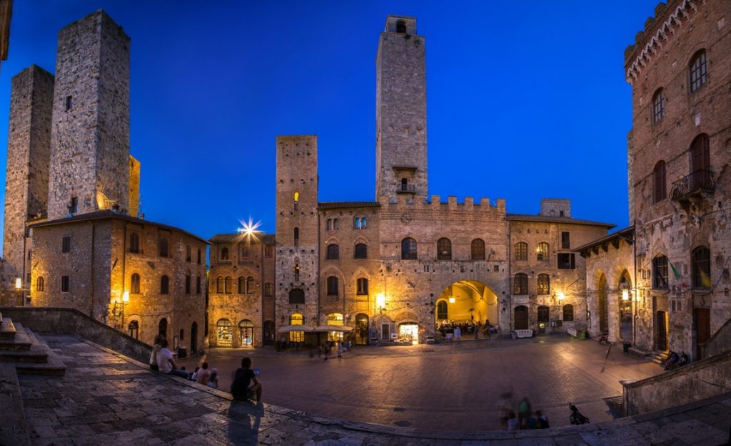 Plaza of a Tuscan hilltop town at night with clear blue sky