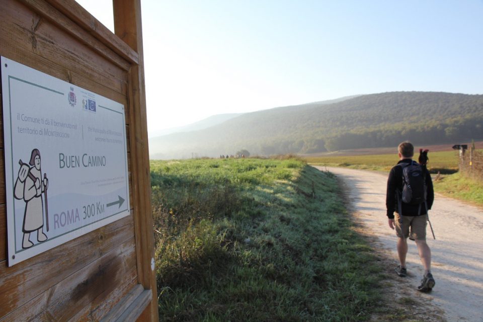A Pilgrim passes a sign for the Via Francigena