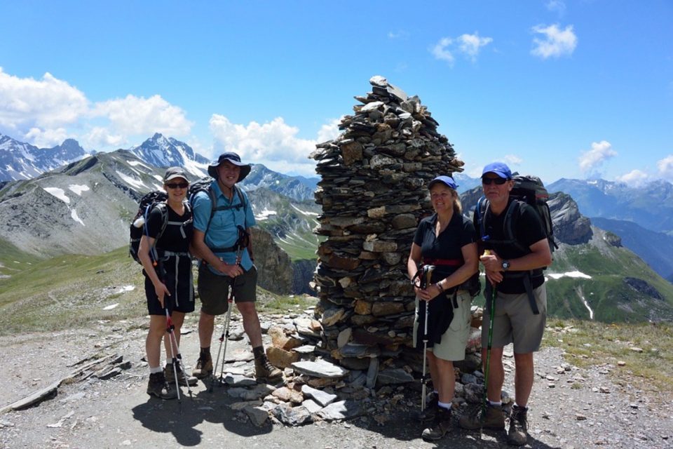 Four hikers next to a stone stacked marker.