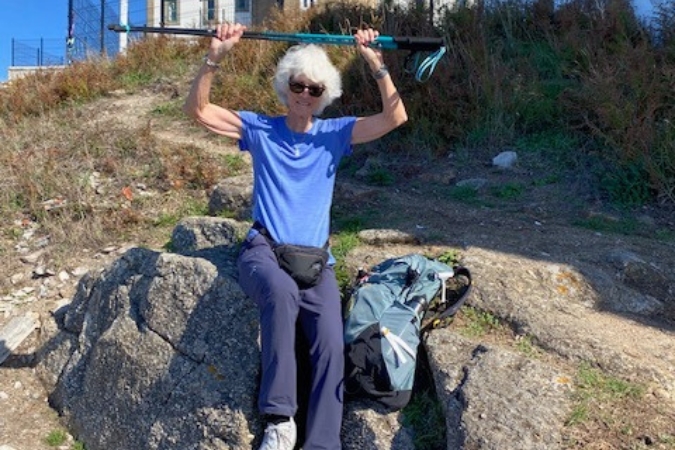 A female hiker on the Camino holding her trekking poles in celebration.