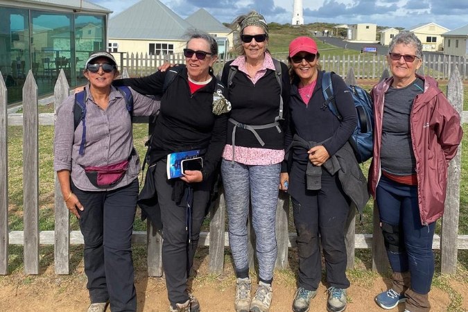 Group of five female hikers in warm hiking gear huddled together on the Cape to Cape Track