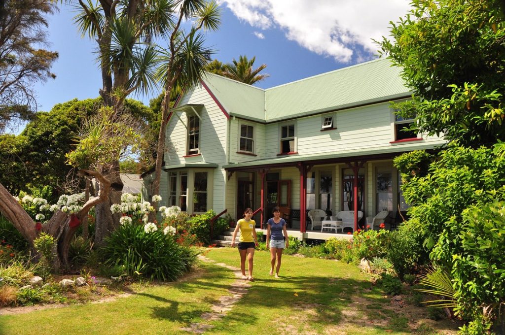 Two travellers in front of a boutique lodge on the South Island