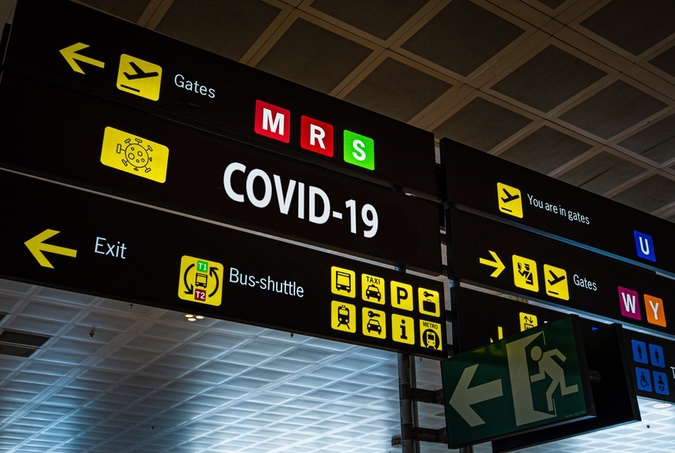 Information panel with Covid-19 word on it at an international airport. Information panel with Covid-19 word on it at an international airport, symbolizing the global spread of the coronavirus through global air traffic
