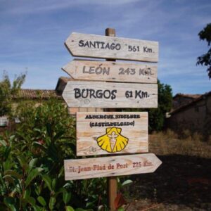 A wooden sign on Spain's Camino de Santiago showing the various distances to Santiago, Burgos and Leon.