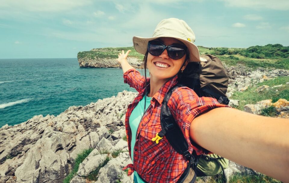 A woman arms outstretched with the Camino del Norte in the background.