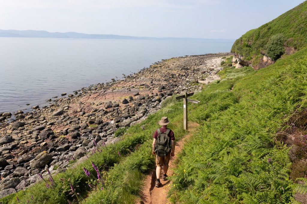 Walker along path which traces the coast of Arran