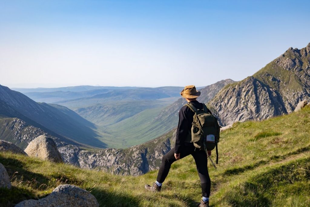Male hiker standing on a rocky mountain facing a valley on the Isle of Arran, Scotland.