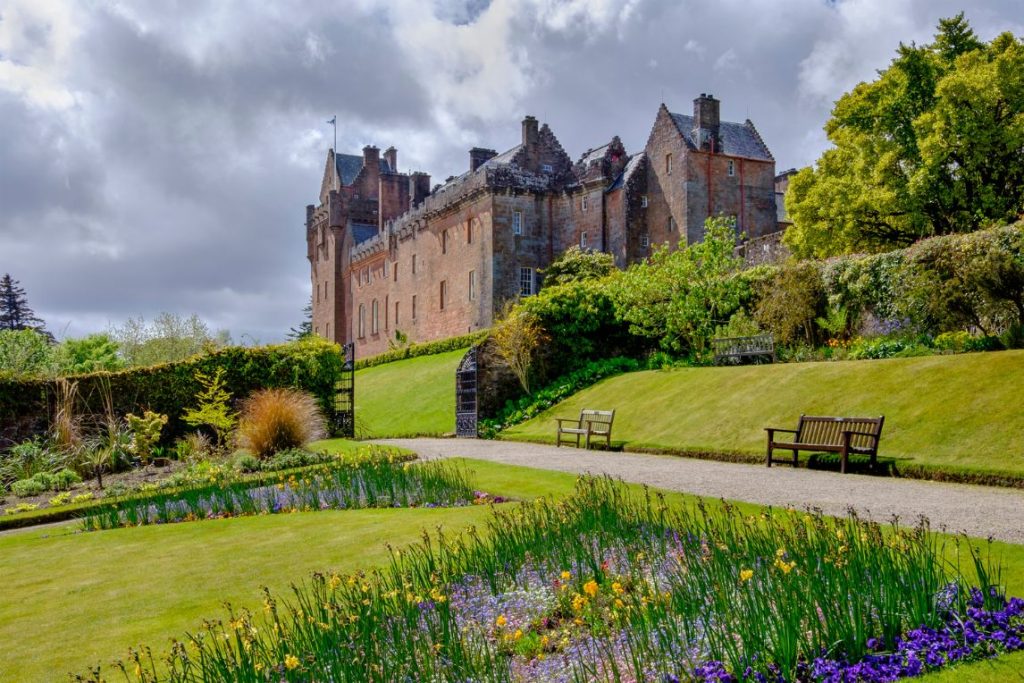 Exterior of a large grand Brodick Castle with grass and flowers in the foreground on the Isle of Arran, Scotland.