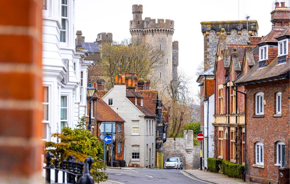 A picturesque residential English street with a majestic castle in the background.