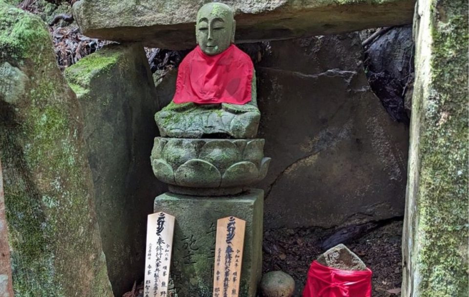 Buddha statue sitting peacefully on stone shrine.