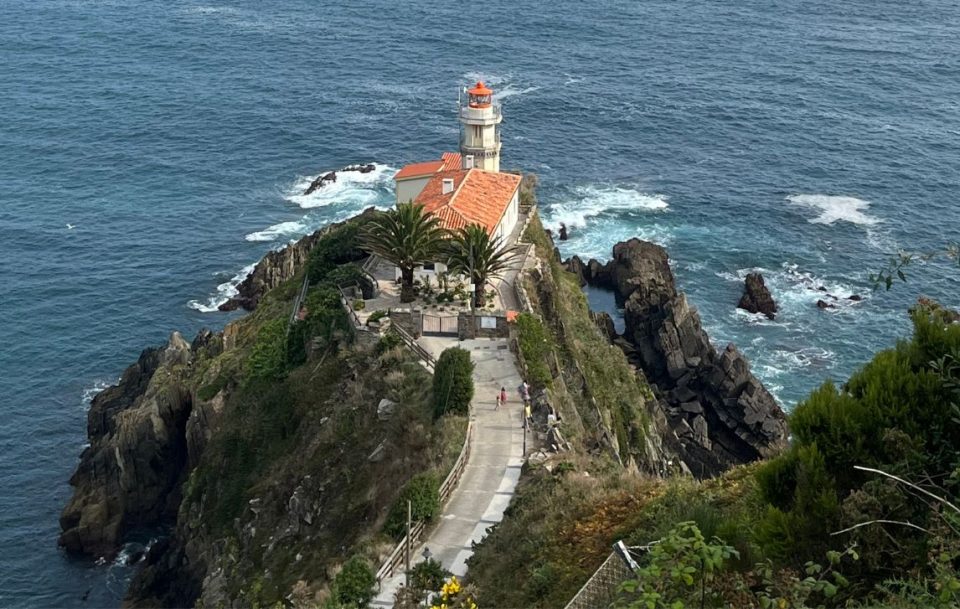 A lighthouse stands majestically on a rocky cliff, providing a stunning view of the vast ocean below.