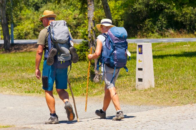 Two walkers with backpacks and hiking poles on a path on the Camino de Santiago
