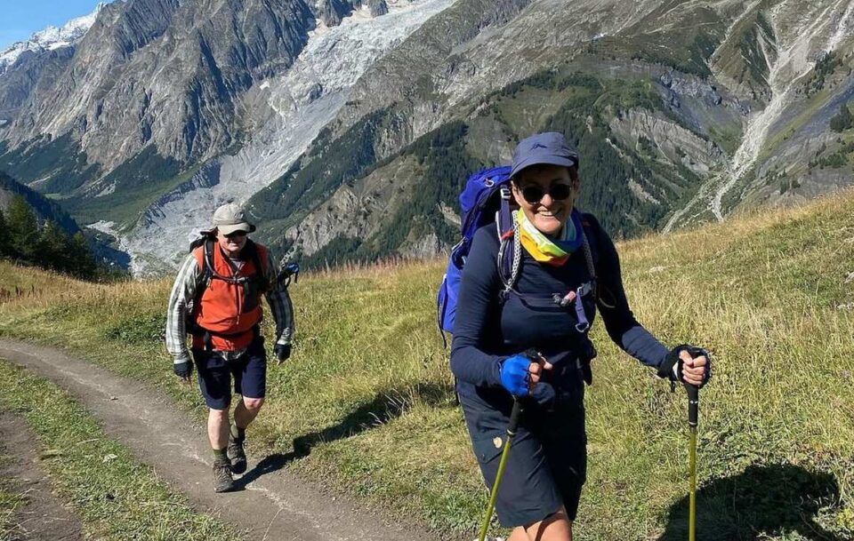 Two hikers walking towards the photographer with the Alps in the background.