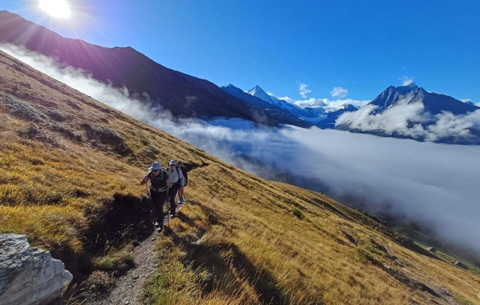 Hikers walking along a narrow trail high above the clouds on Switzerland's Walker's Haute Route.