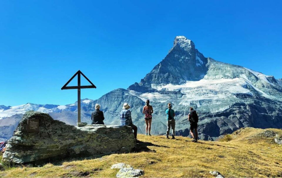 Peak hikers stop with Alps in background