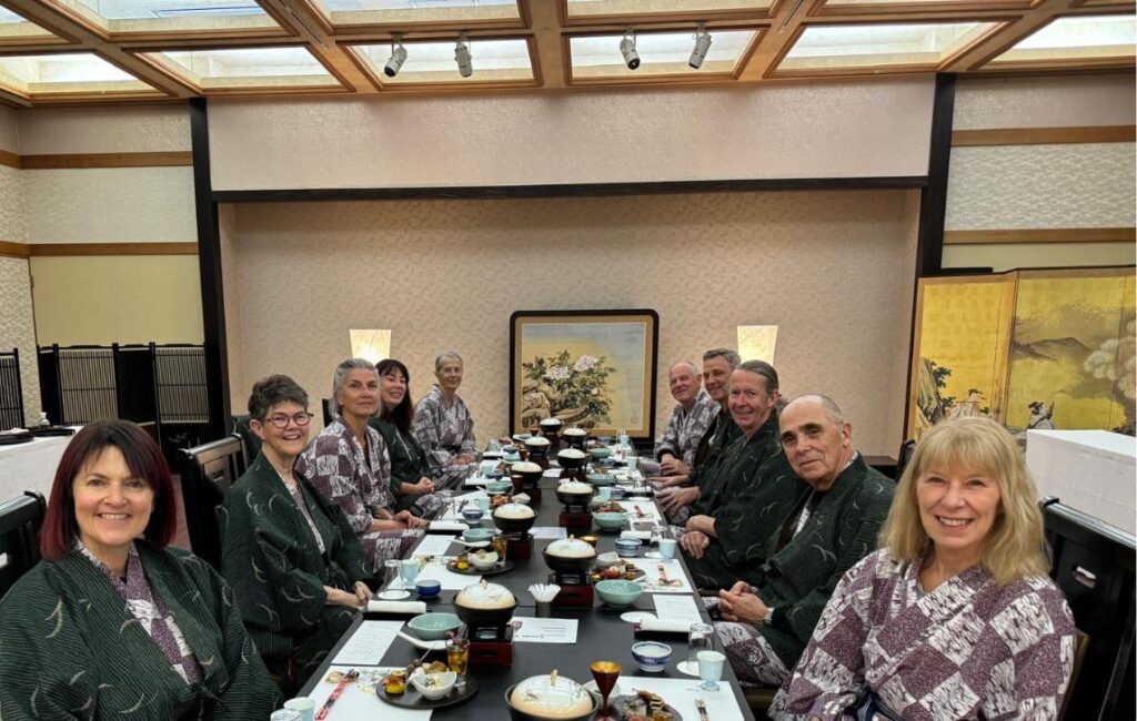 A long table full of hikers sitting down to a traditional Japanese meal at a Japanese style restaurant.