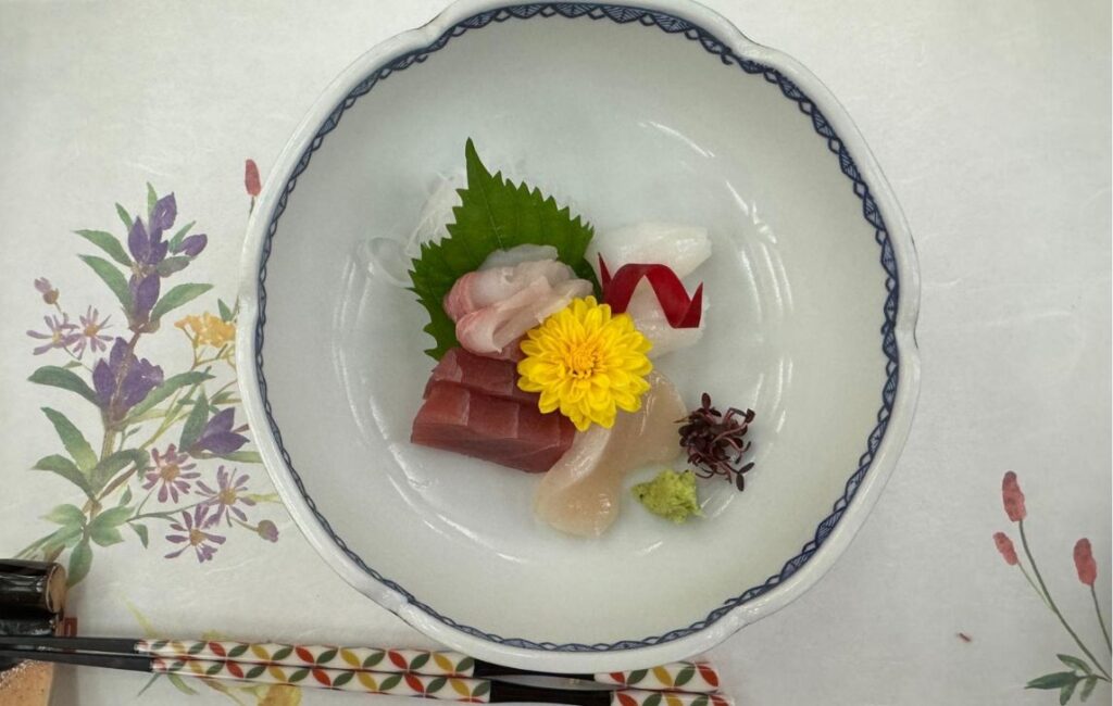 A beautiful bowl of sashimi presented with edible flowers.