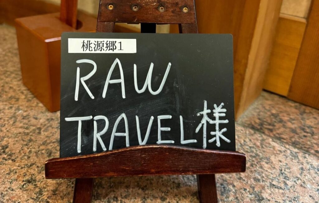 A chalk board sign saying Raw Travel in English and Japanese.