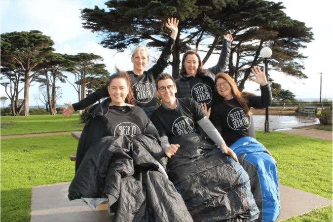 Sleeping in car fundraiser A group of perople huddles wearing ponchos to celebrate sleeping in your car fundraiser