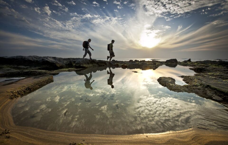 Silhouette of two hikers walking along a beach on the Great Ocean Walk
