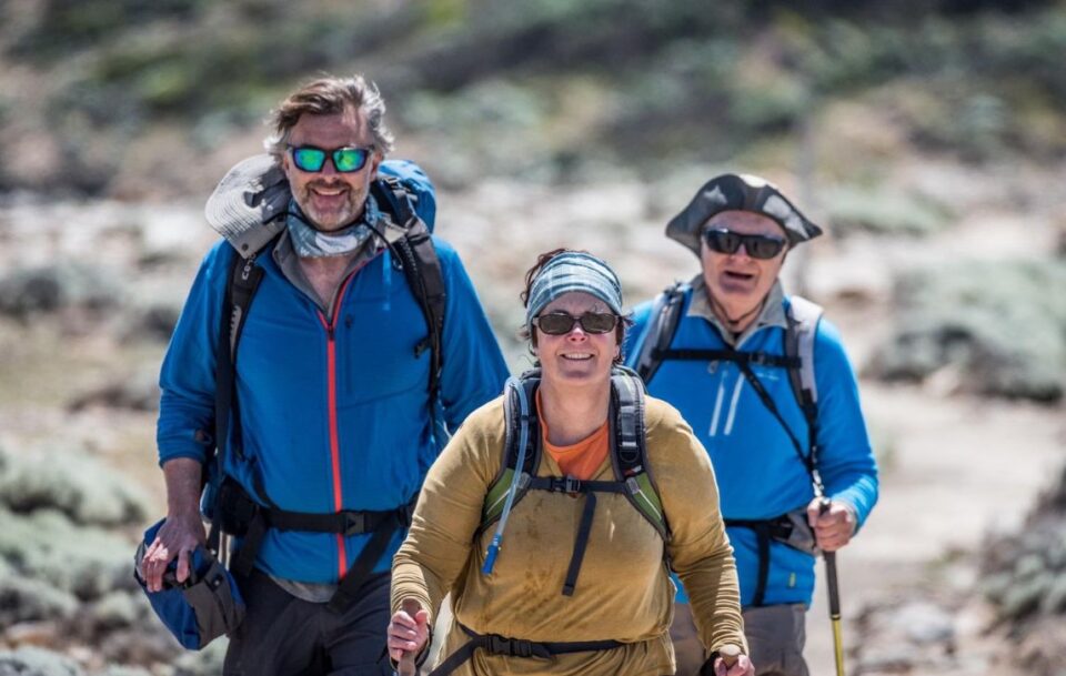 Three hikers in blue jackets smiling at the camera
