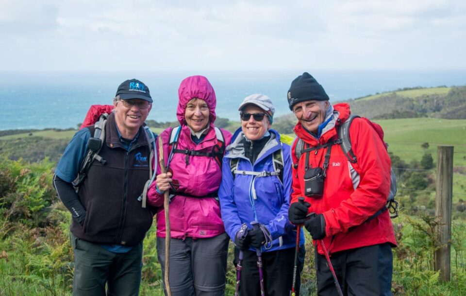 A group of hikers on the Great Ocean walk wearing rain gear and smiling at camera.