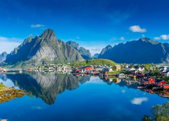Lofoten Islands Norway. Picturesque village with red fishing huts sitting on the edge of a lake with the mountains behind them. Lofoten Islands Norway.