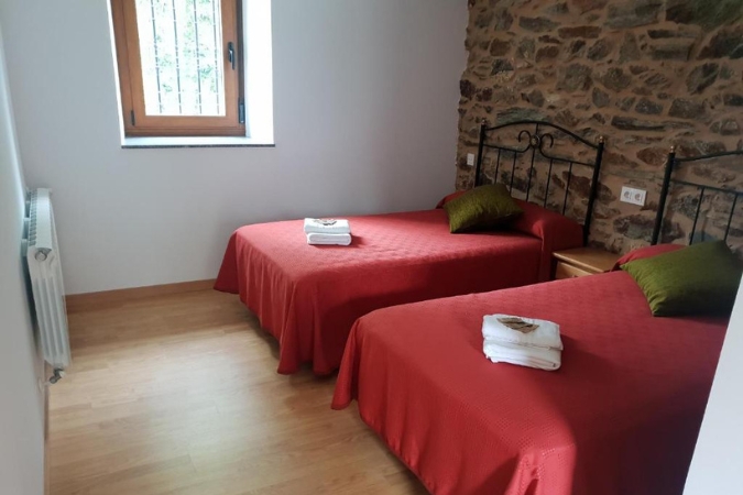Interior of a basic hotel room on the Camino Primitivo with two single beds and a small window
