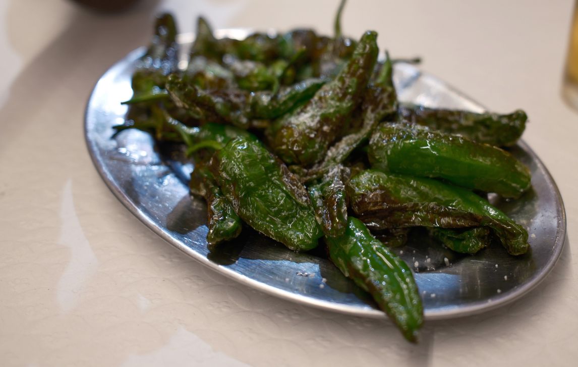 Close-up of charred green peppers on a silver plate in Santiago de Compostela.