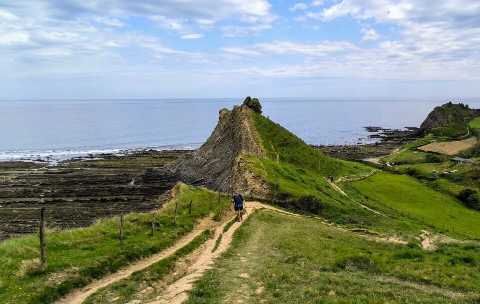 Hiker Camino del Norte Spain A narrow coastal dirt path and a lone hiker on the Camino del Norte in Spain