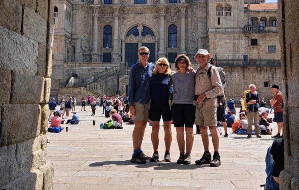 Four hikers standing in front of the Cathedral in Santiago de Compostela, Spain