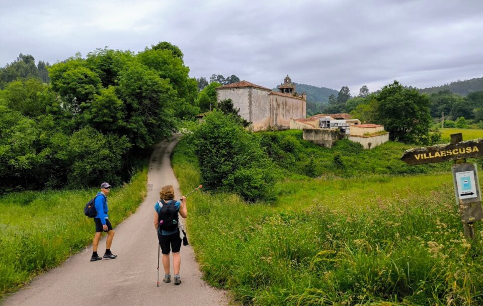 Two hikers on a path surrounded by lush greenery near the village of Villaescusa on the Camino del Norte