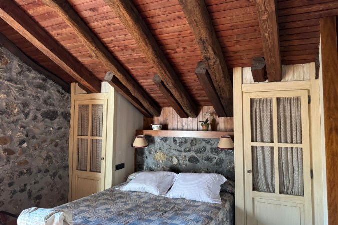 Hotel bedroom interior - Camino del Norte Spain Rustic bedroom on the Camino del Norte with stone walls, wooden beams, and cosy bedding.