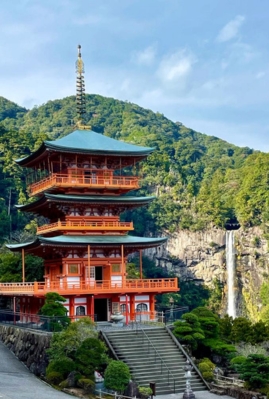 View of Nachi Falls, the main waterfall on the Kumano Kodo pilgrimage trail, cascading beside the iconic Seiganto-ji pagoda in lush forest surroundings.