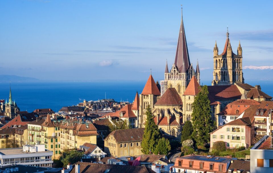 Orange rooftops and spires in Lausanne city with big blue Lake Geneva in the background