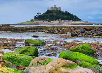 St Michael's Mount, Cornwall St Michael’s Mount in Cornwall, with a rocky shoreline in the foreground covered in bright green moss.