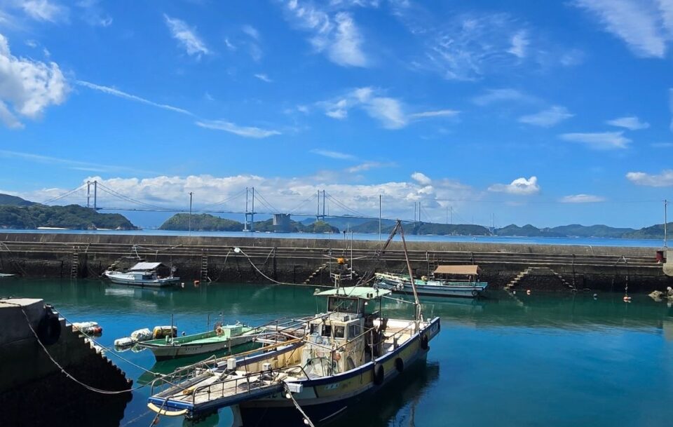Fishing boats in a small harbour with views of the towers of the Tatara Bridge in the background, Shimanami Kaido
