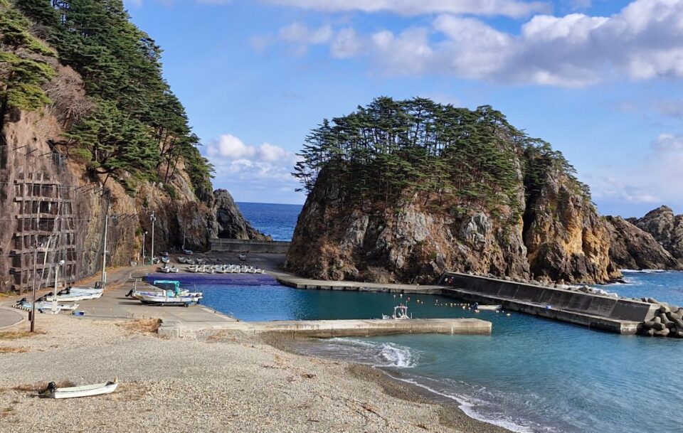 Cliffs and fishing boats and a seawall on Japan's Michinoku Coastal Trail