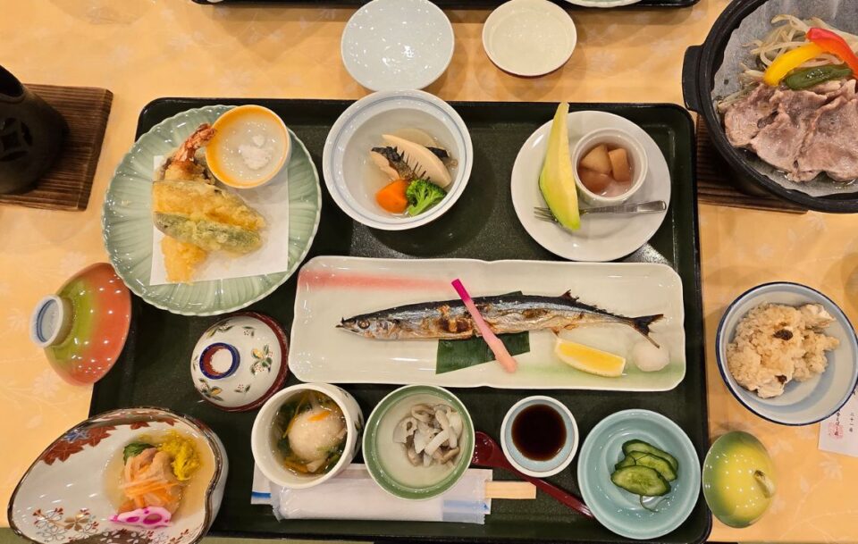 A tray with various bowls of colourful fresh Japanese food, including rice, vegetables fish